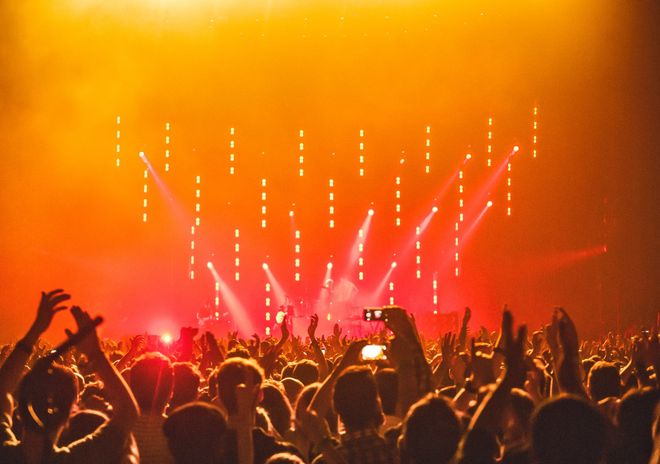 A crowd of people are standing in front of a stage at a concert.
