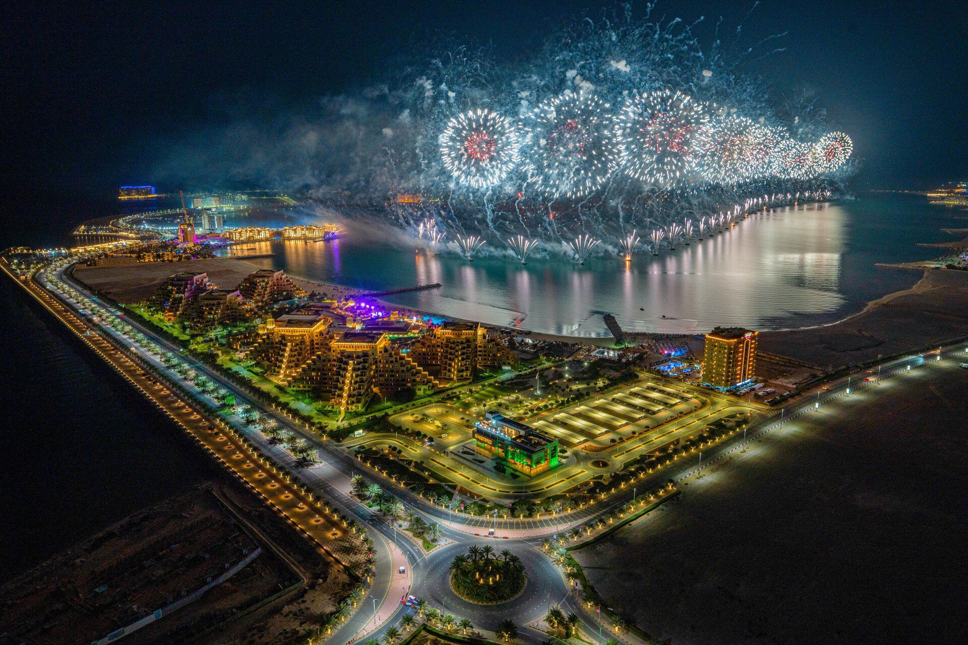 An aerial view of a fireworks display over a city at night.