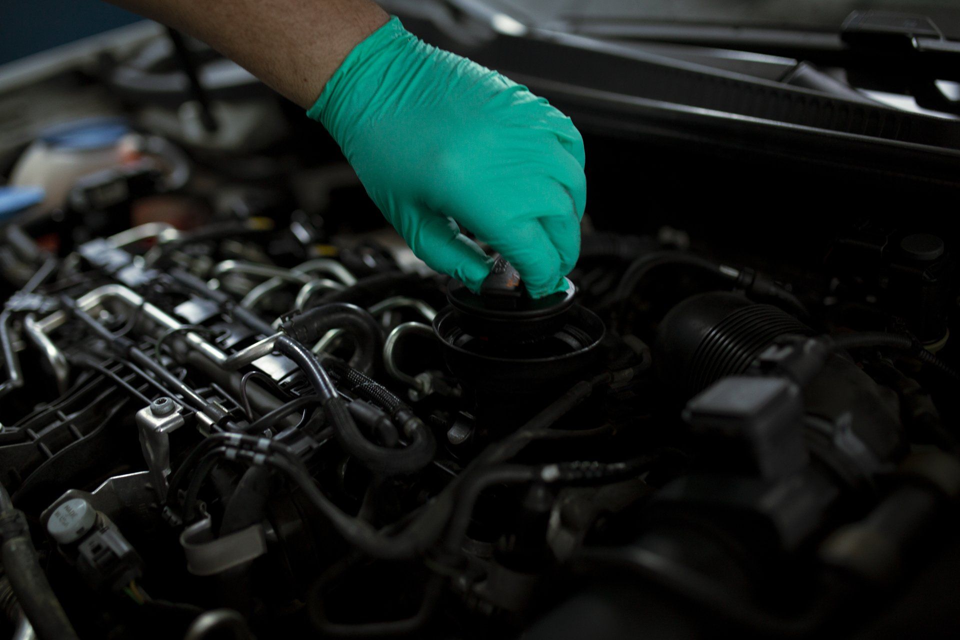 a person wearing green gloves is working on a car engine .