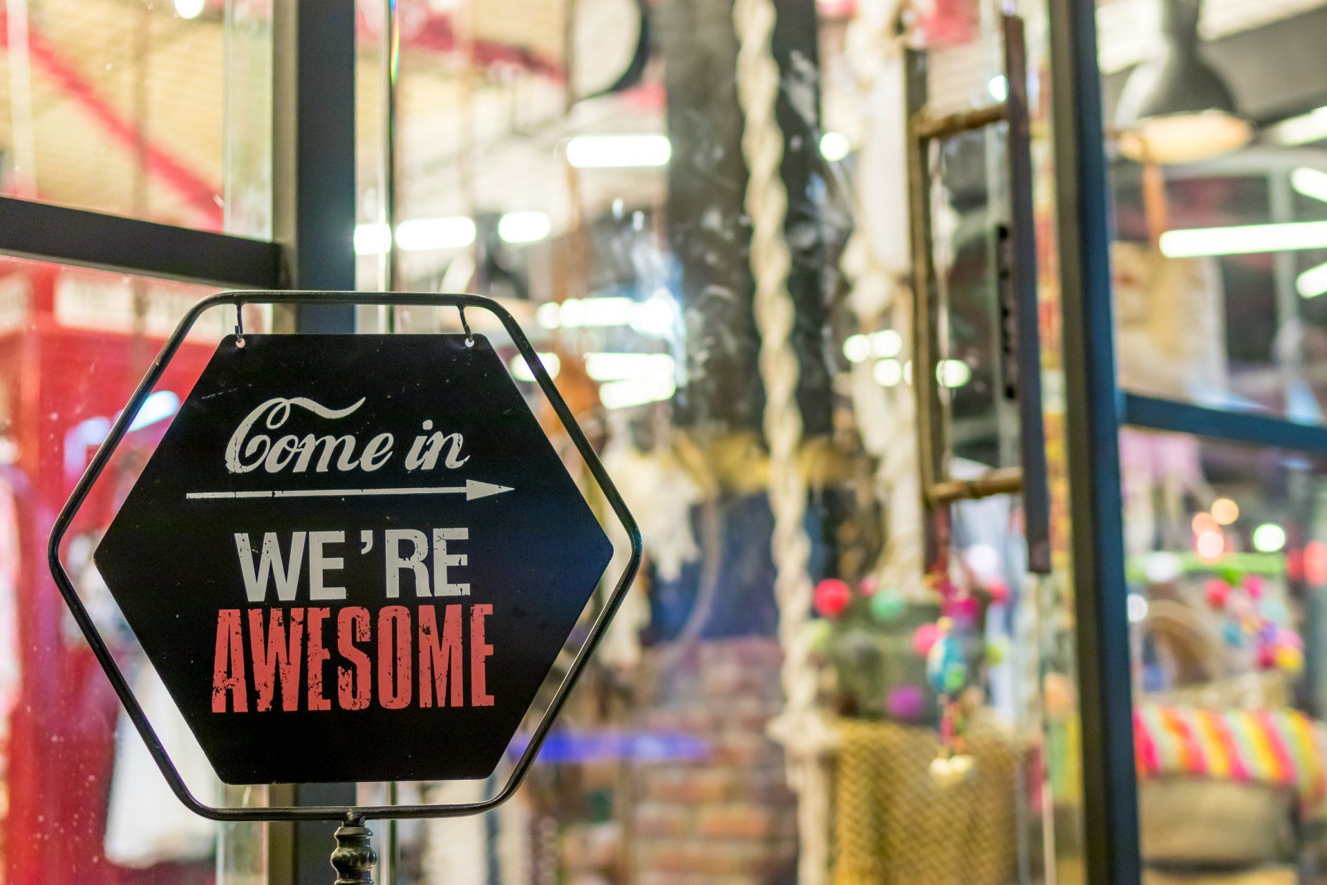 A sign that says `` come in we 're awesome '' is hanging in a store window.
