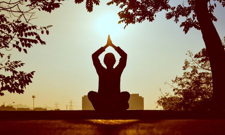 A person is sitting in a lotus position with their hands in the air.