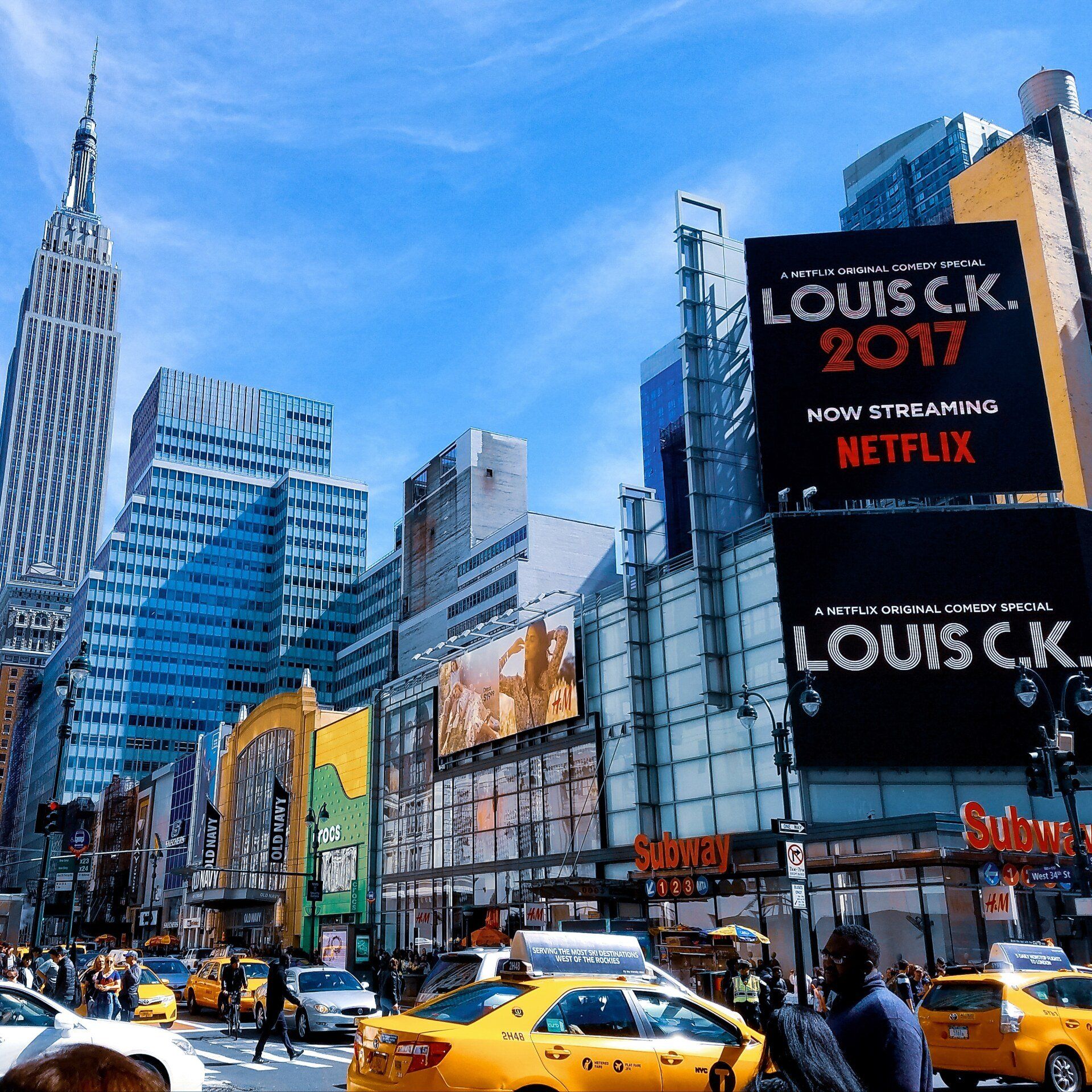 Una concurrida calle de la ciudad con un cartel que dice louis ck 2017