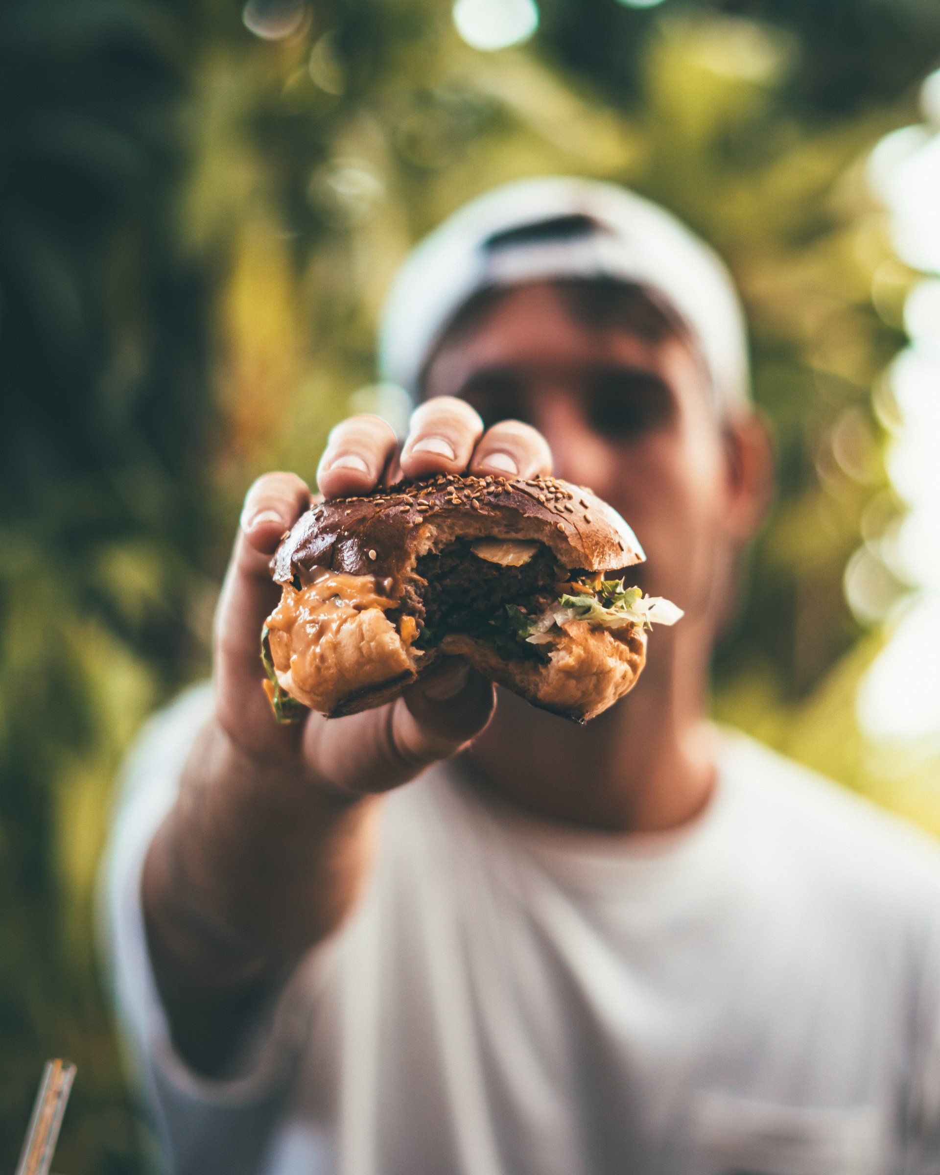 a man is holding a hamburger in his hand with a bite taken out of it .