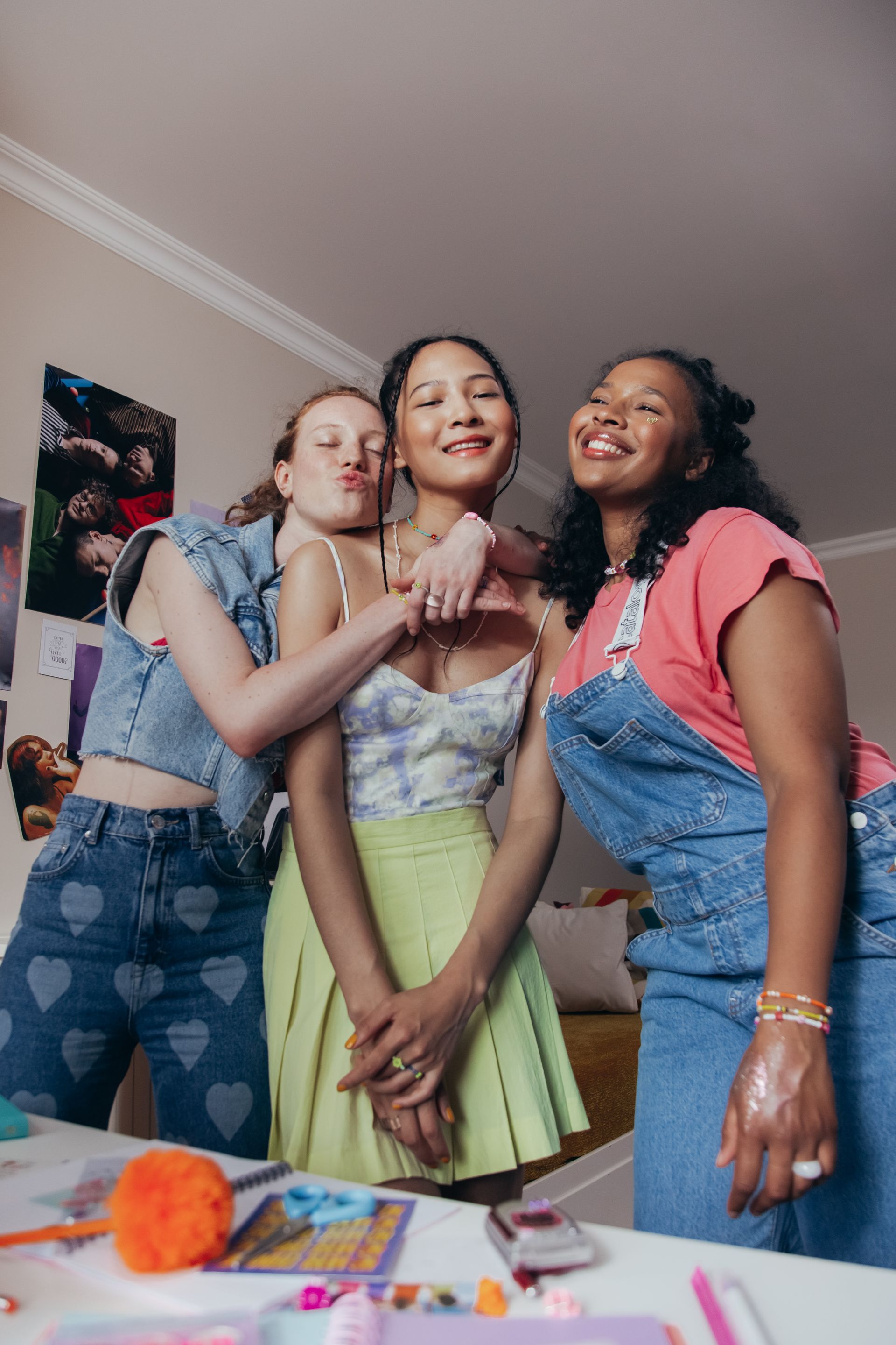 Three young women are posing for a picture together in a room.
