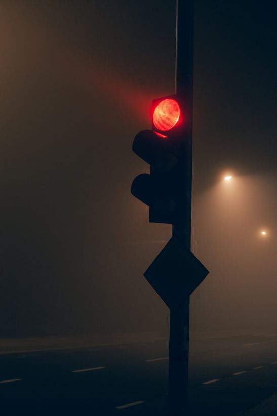 Stark red stoplight beams out on a dark street.