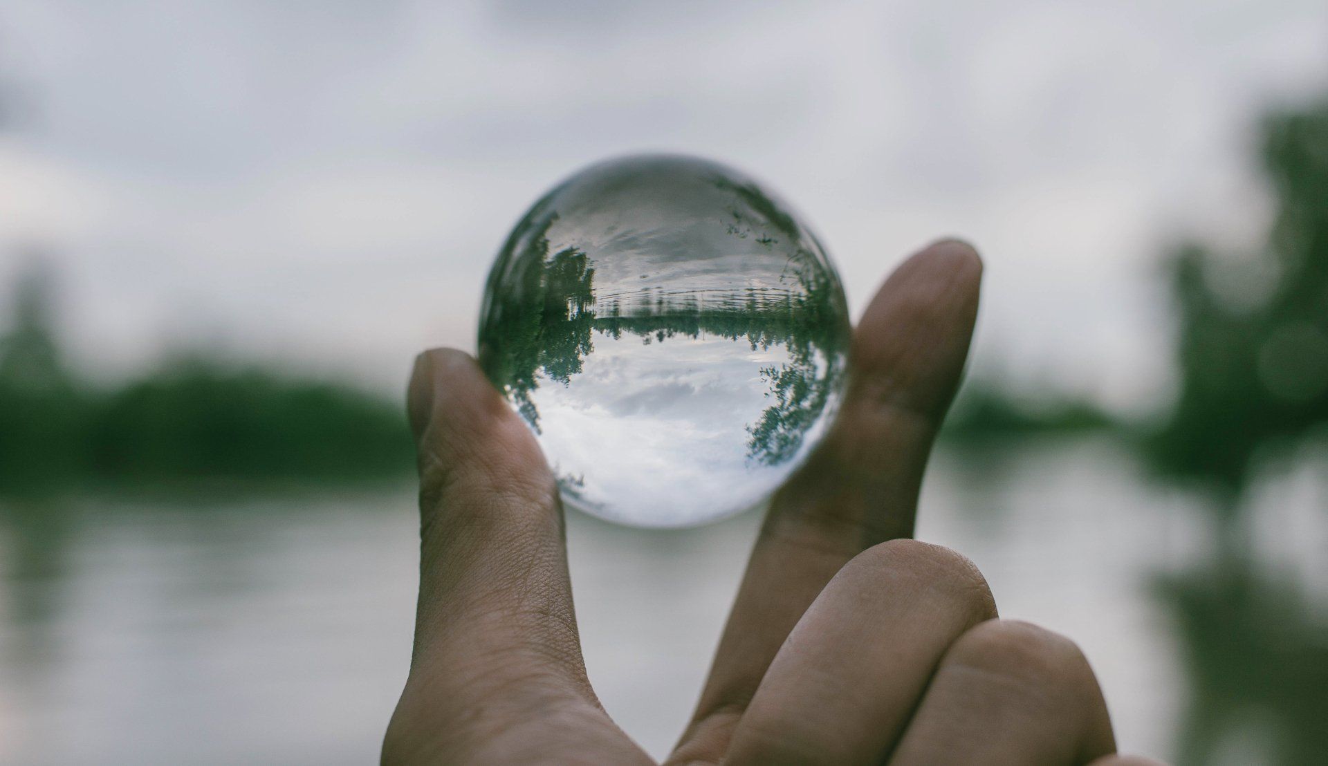 A person is holding a clear glass ball in their hand.