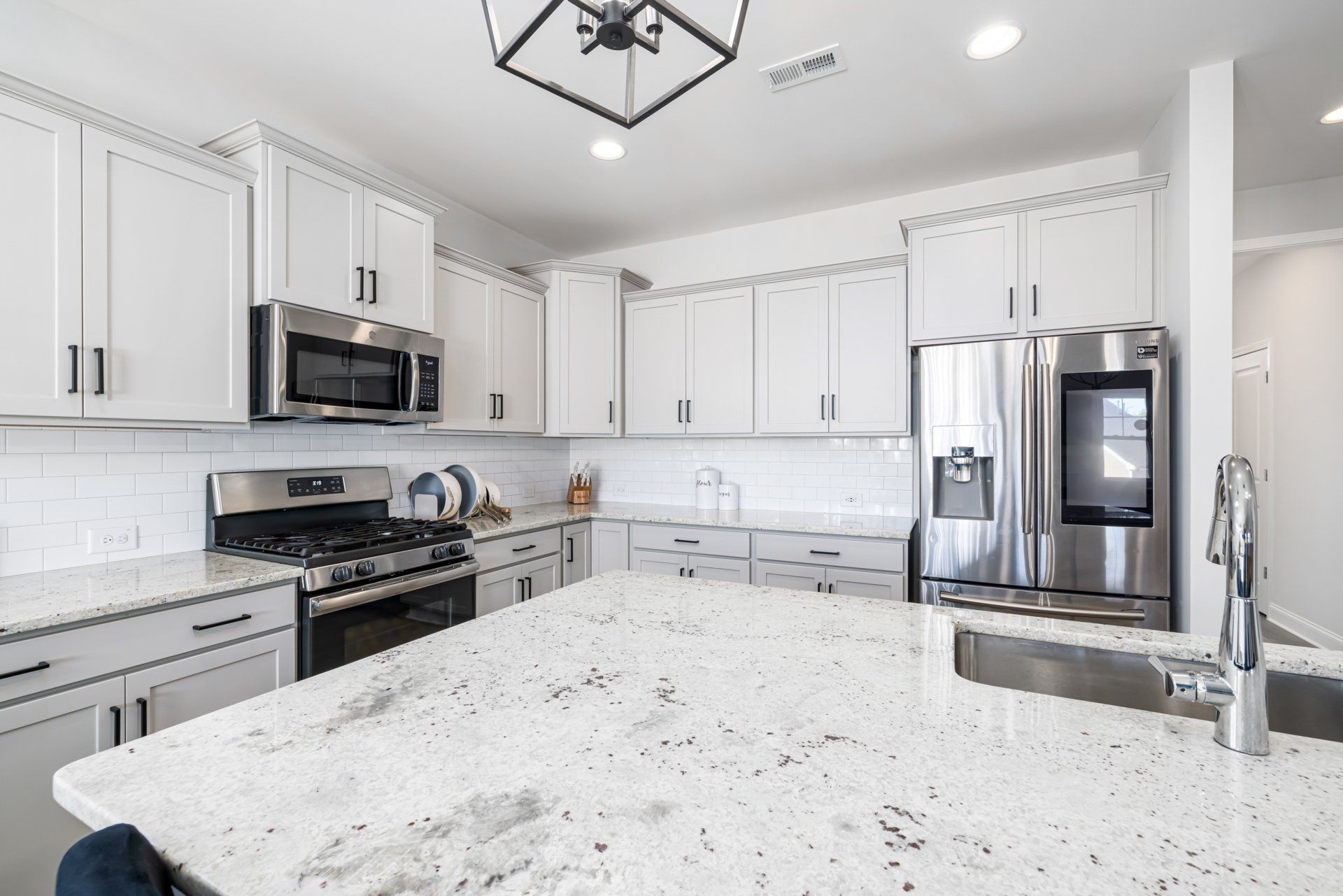 Kitchen with white cabinets, white granite, and stainless steel appliances