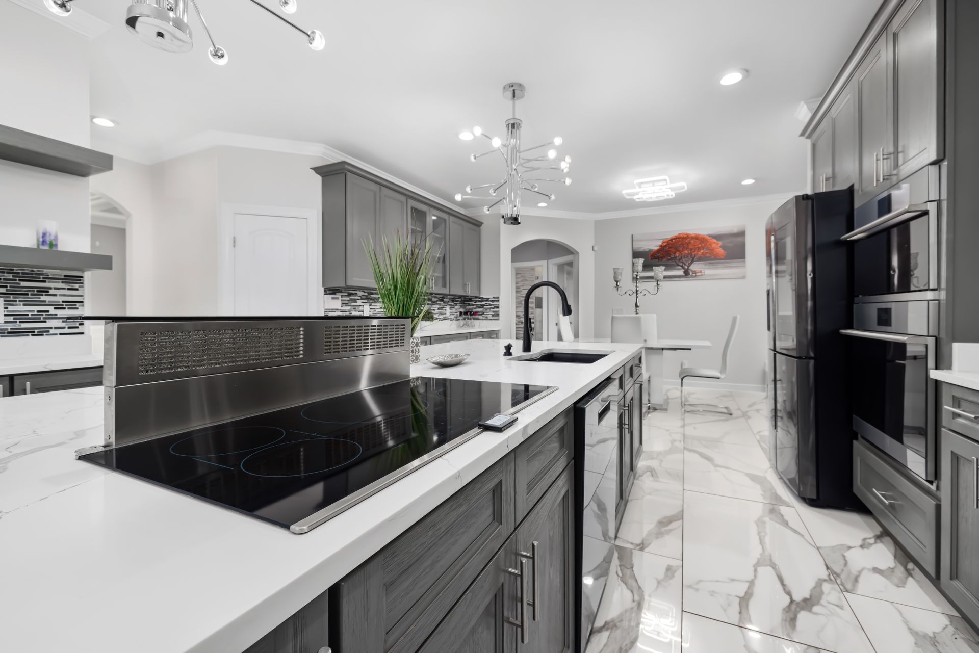 a kitchen with gray cabinets , white counter tops , a stove top oven , a refrigerator and a sink .