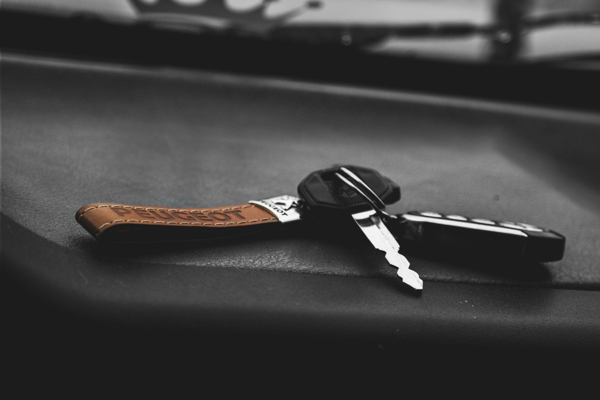 A pair of car keys laying on the dashboard of a car.