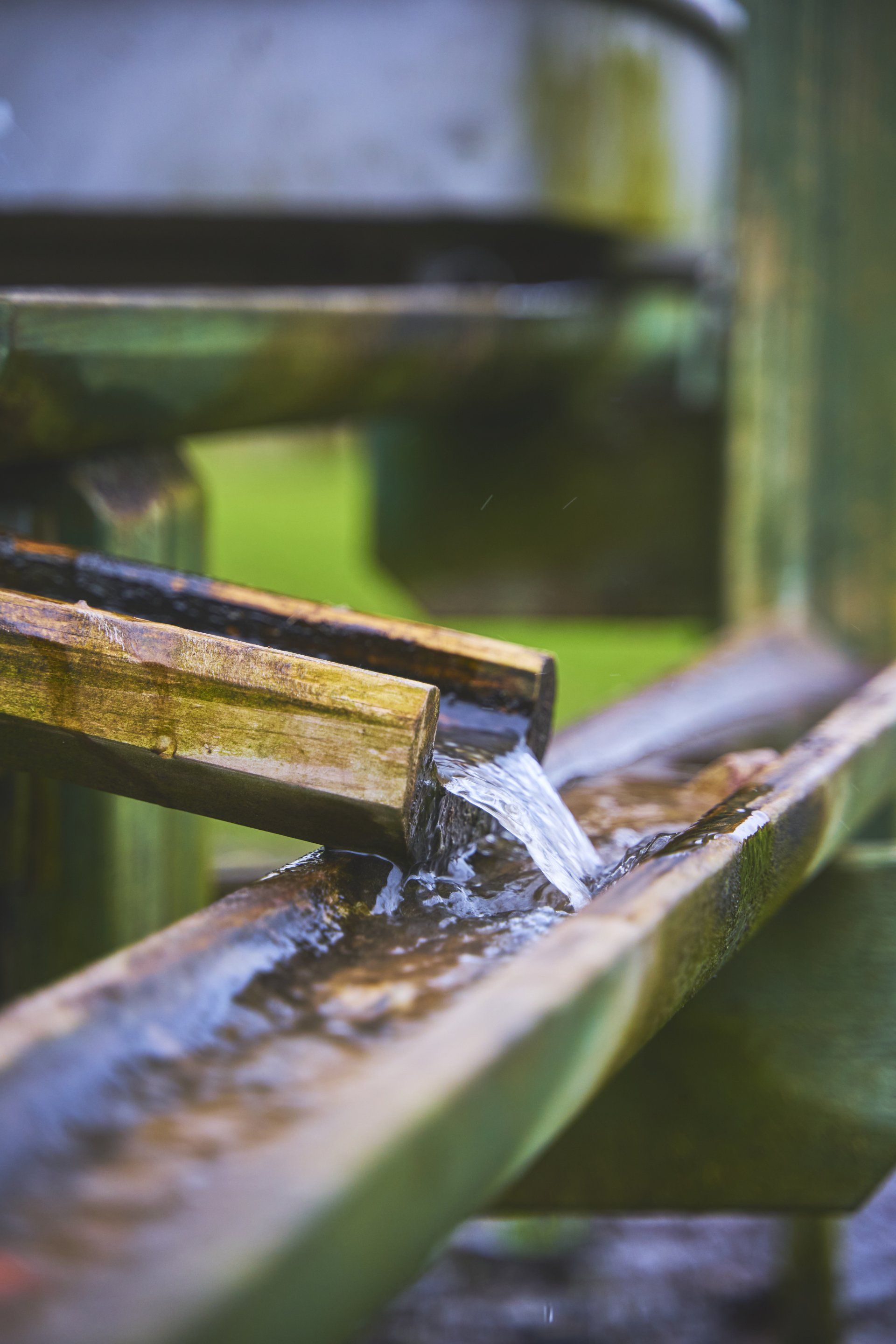 a stream of water is coming out of a wooden pipe .