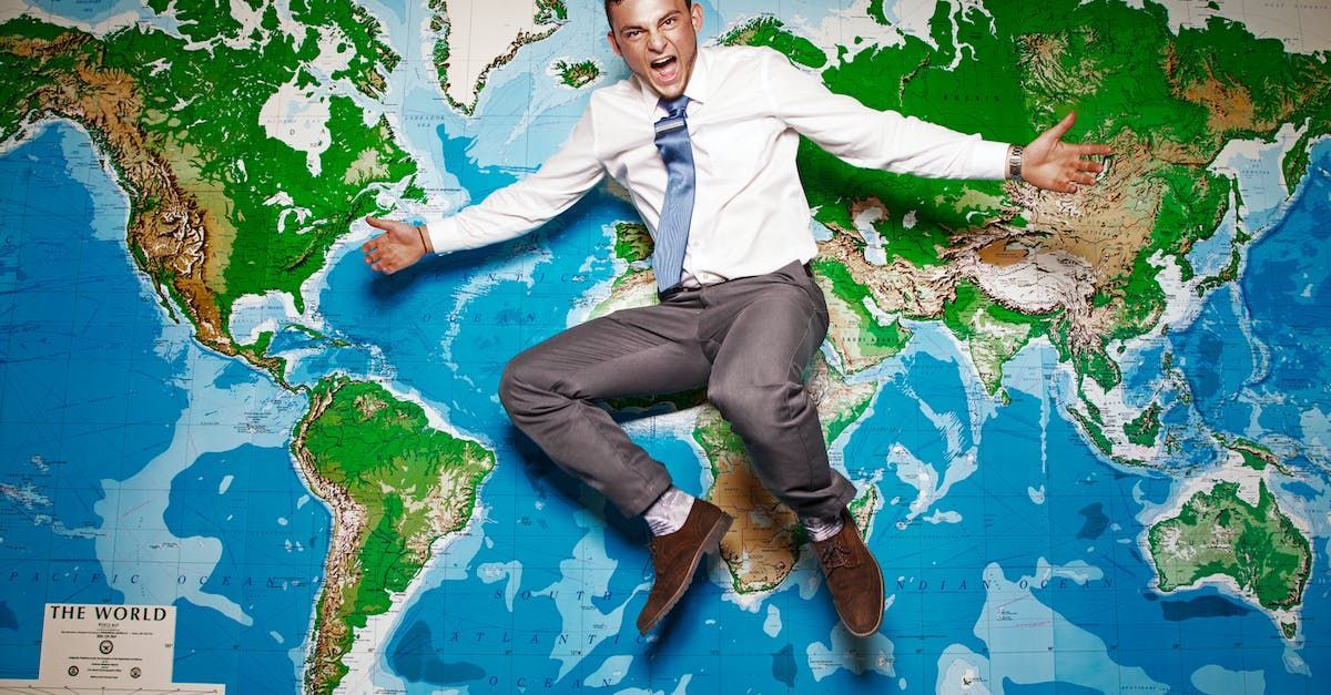 a man is jumping in the air in front of a map of the world .