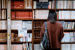 A woman is standing in front of a bookshelf in a library.