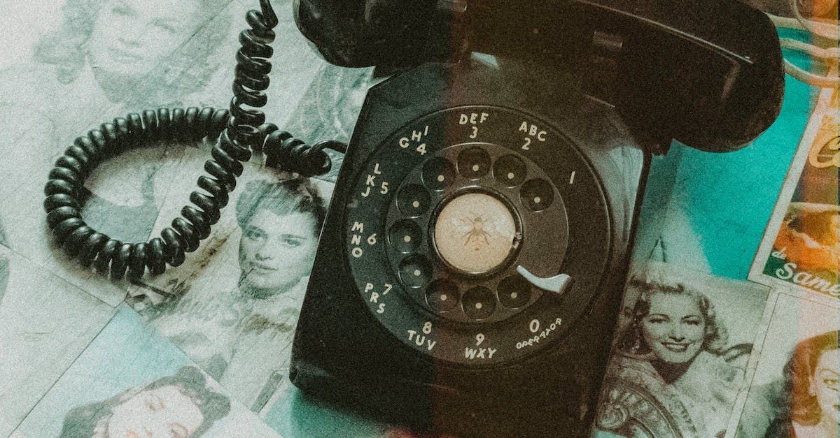 an old black telephone is sitting on top of a collage of pictures .