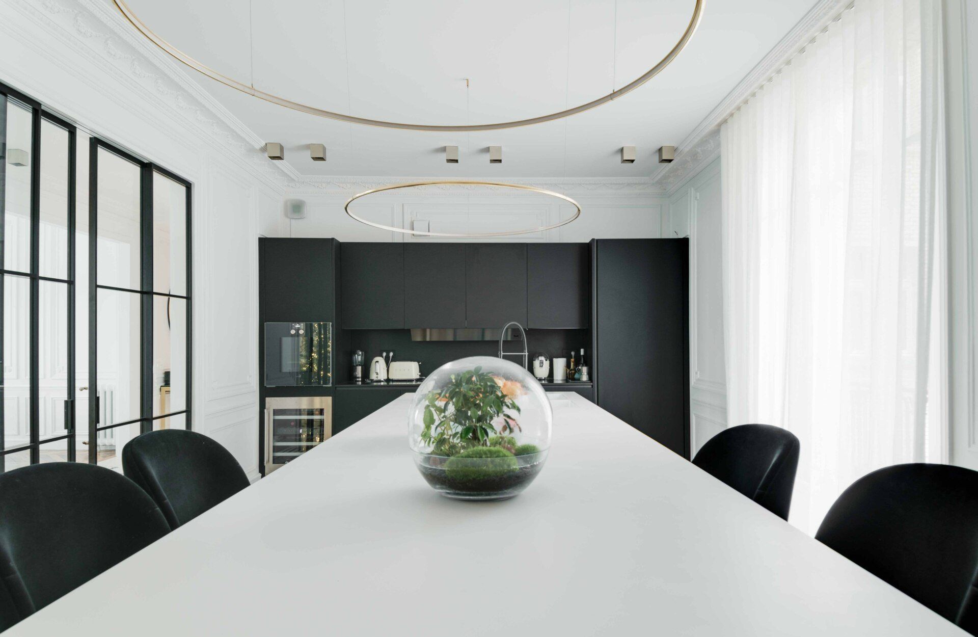 A dining room with a long white table and black chairs.