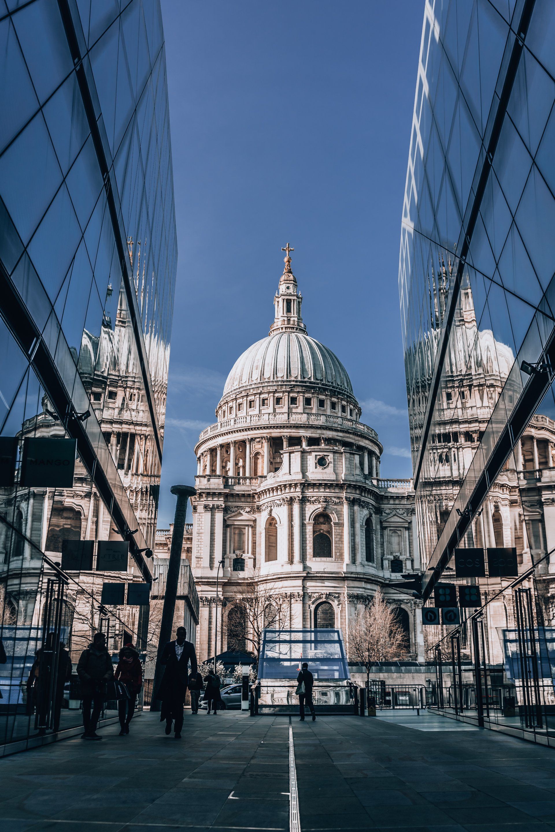 A large building with a dome is reflected in the glass of a building.