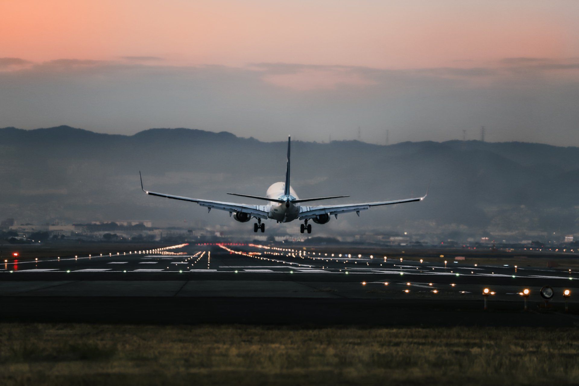 An airplane is taking off from an airport runway at sunset.