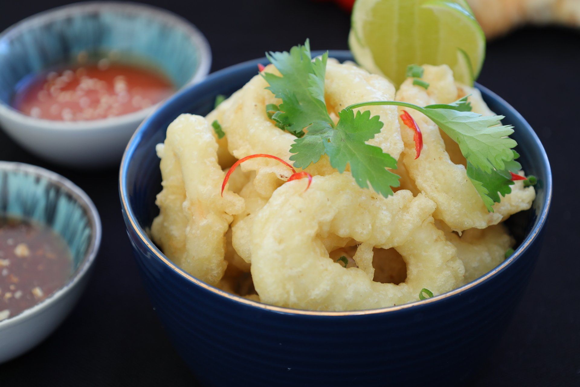 A bowl of fried squid with sauce on a table.