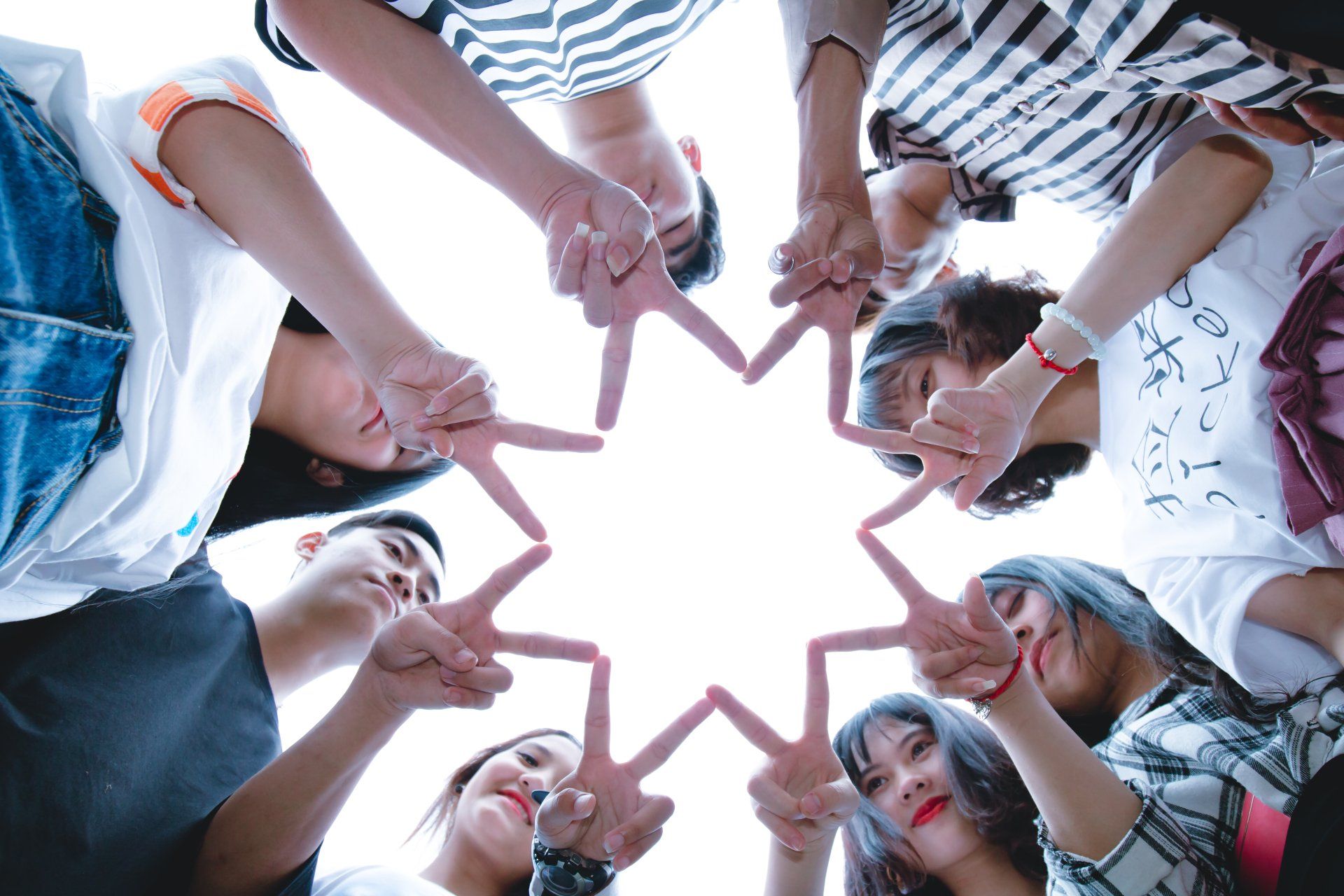 A group of people are making a star with their hands in a circle.