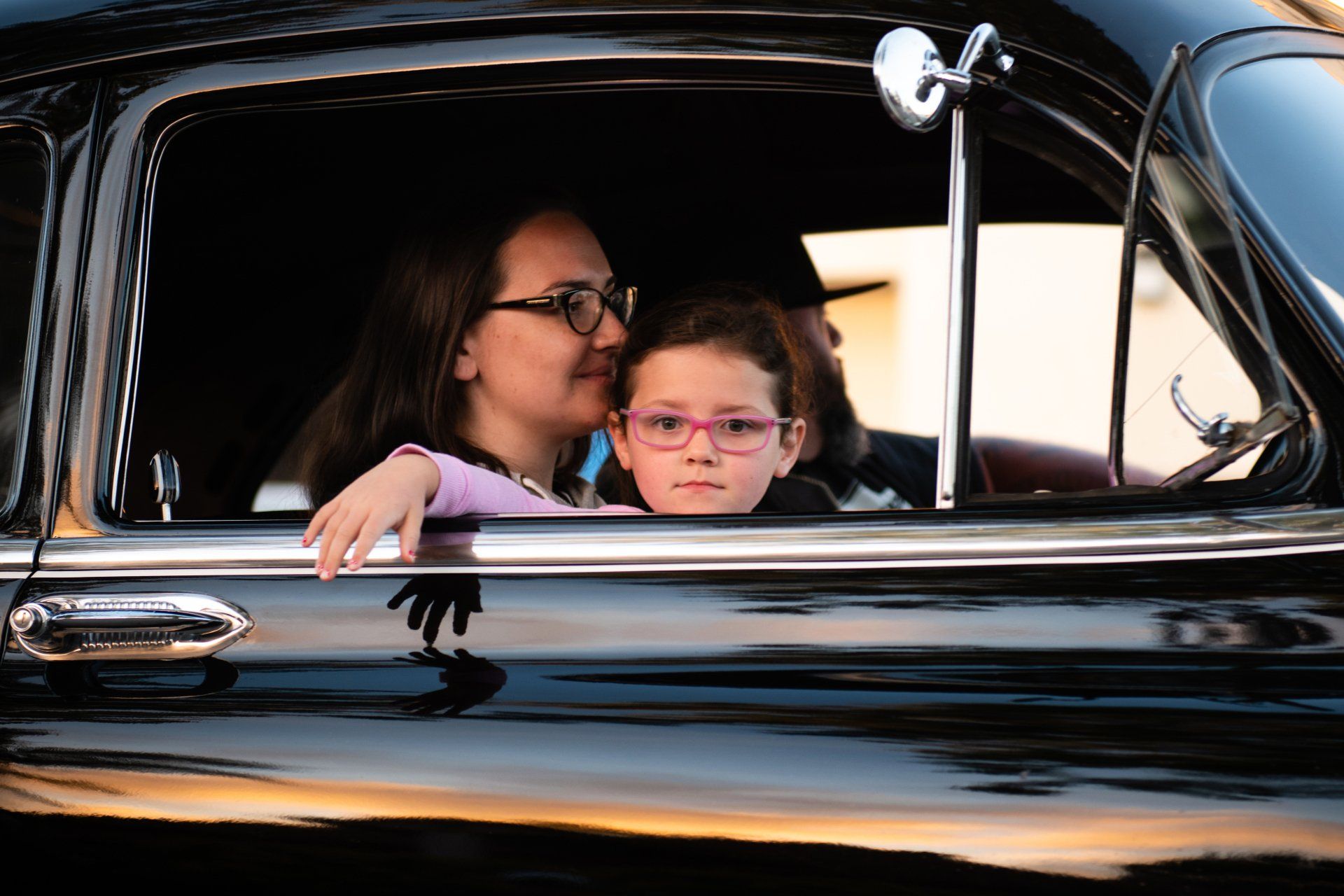 a woman and a child are sitting in a car looking out the window .