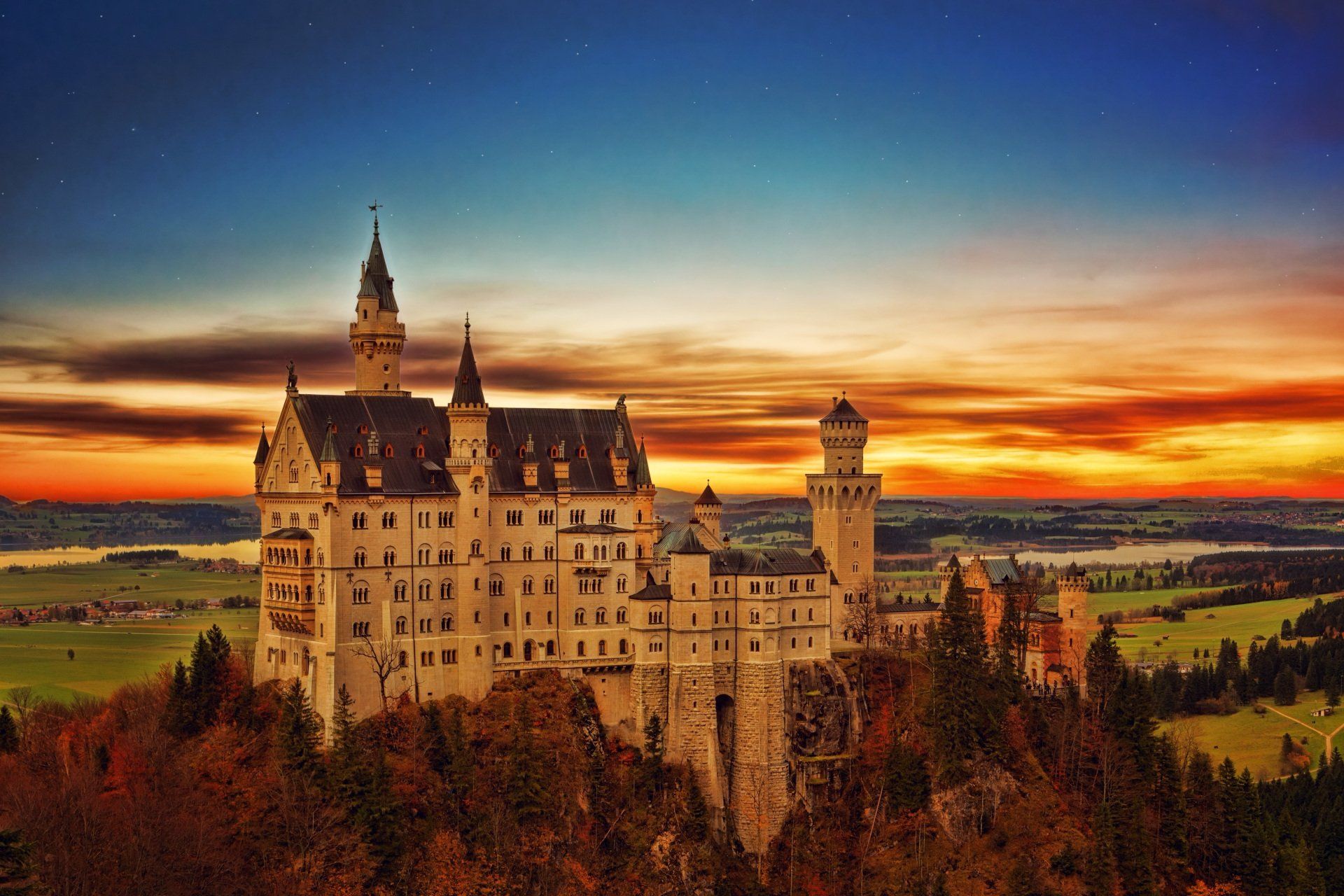 A large castle is sitting on top of a hill at sunset.