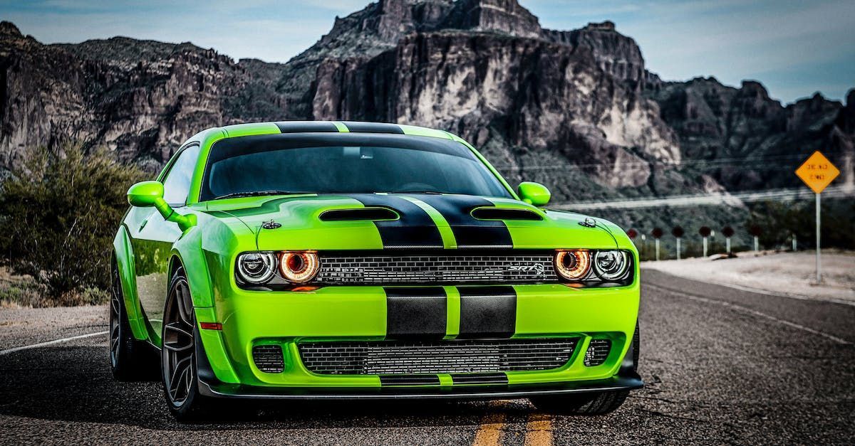 A green dodge challenger is parked on the side of the road.