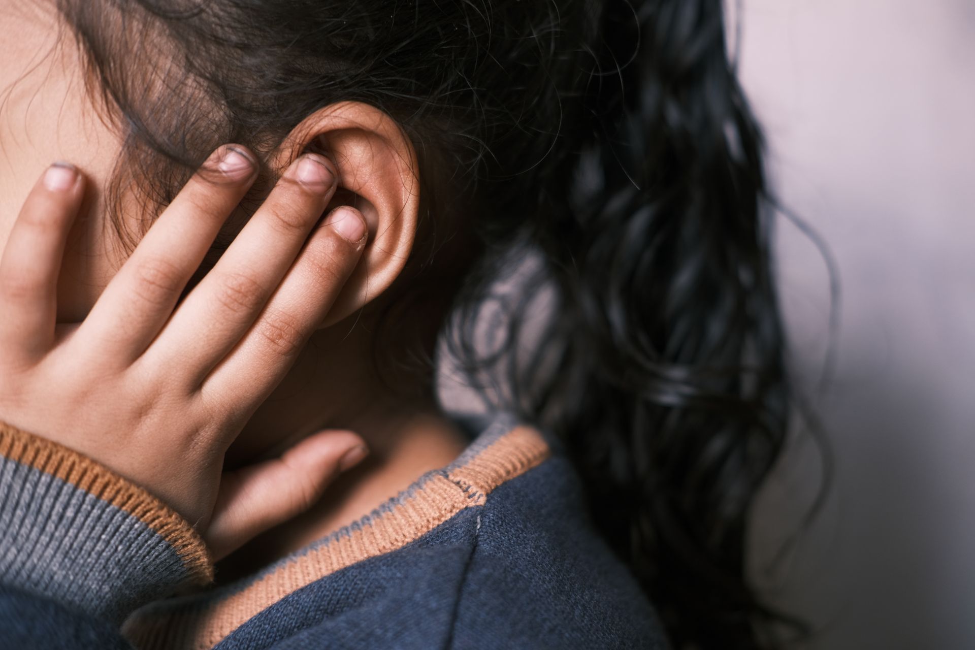 A little girl is covering her ears with her hands.