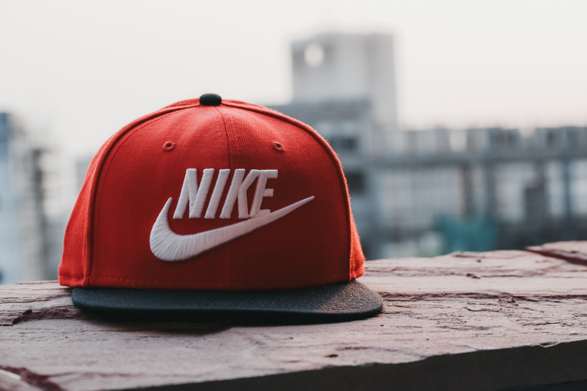 a red nike hat is sitting on a brick wall .