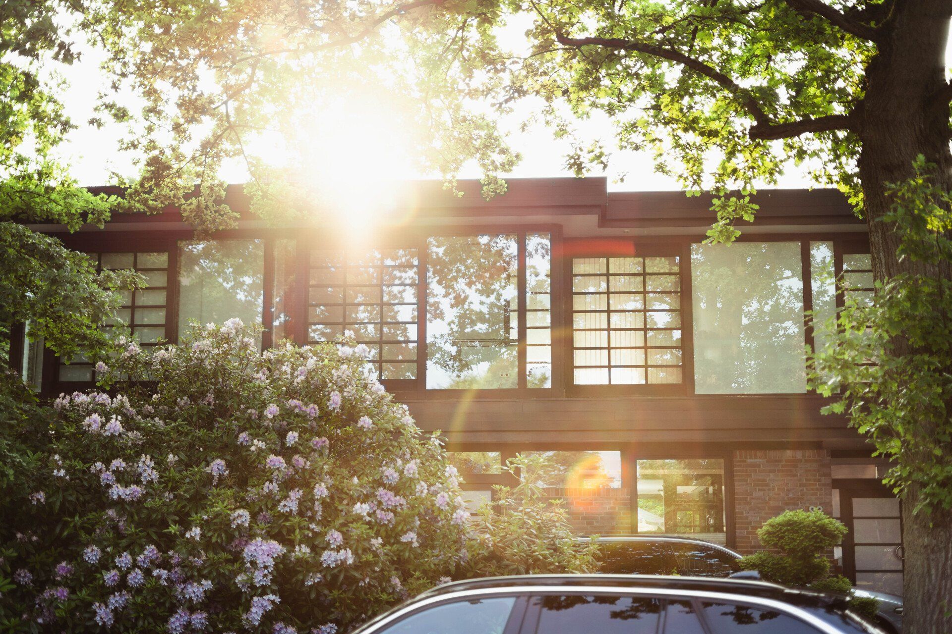 a car is parked in front of a house with the sun shining through the windows