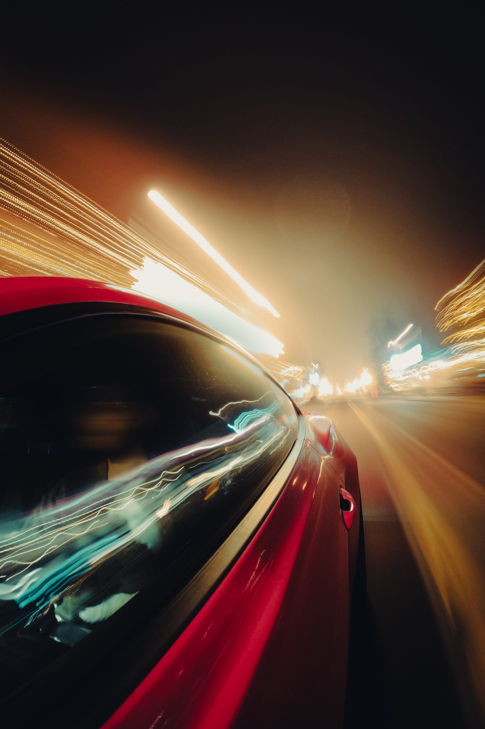 A shiny futuristic car driving very fast with lights streaking into the background