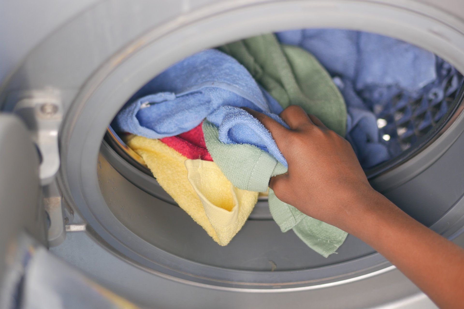 una persona sta mettendo i vestiti in una lavatrice
