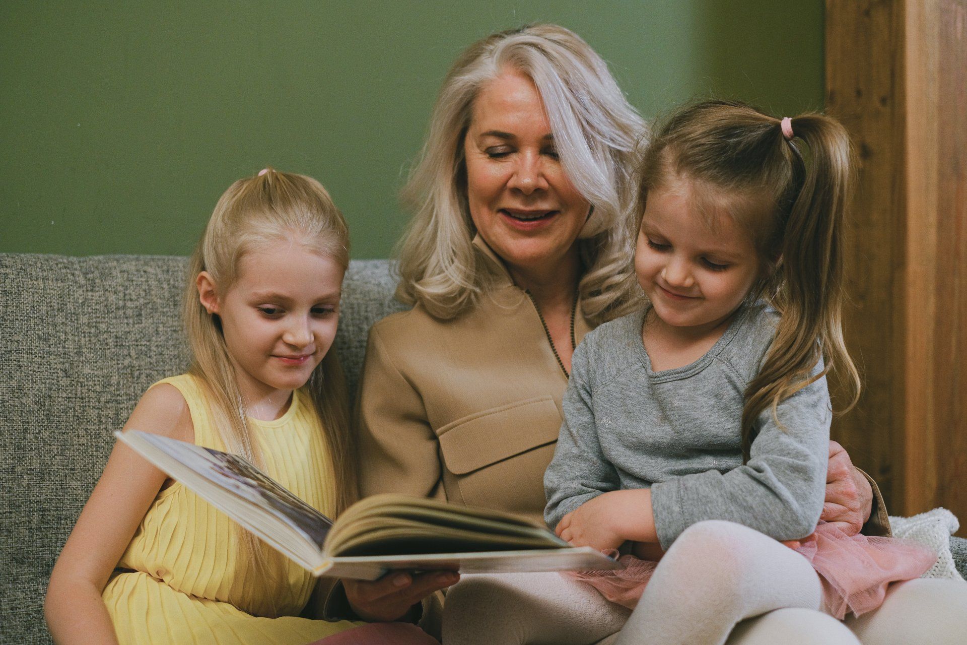 An elderly woman is reading a book to two little girls.