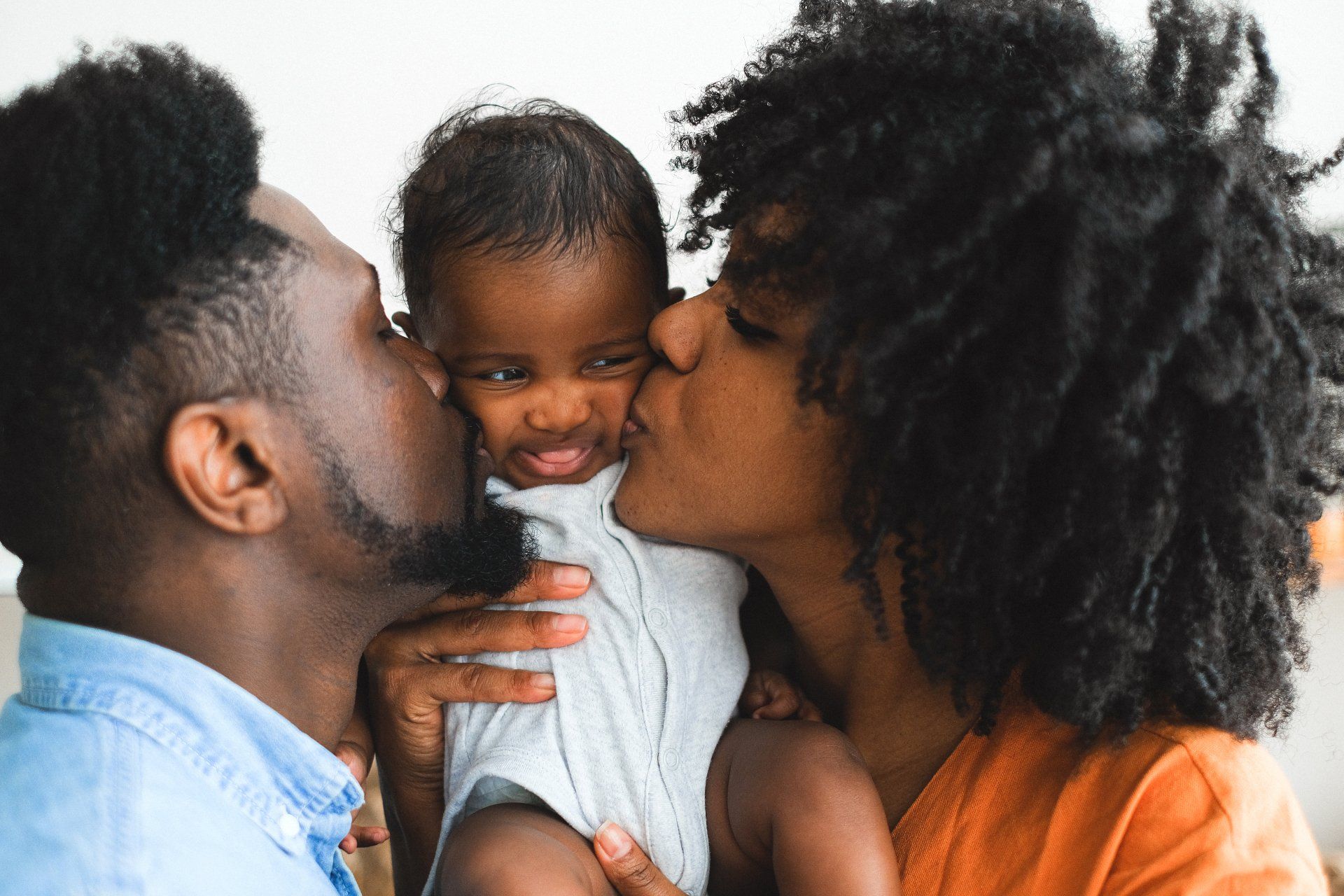 a man and woman are kissing a baby on the cheek 