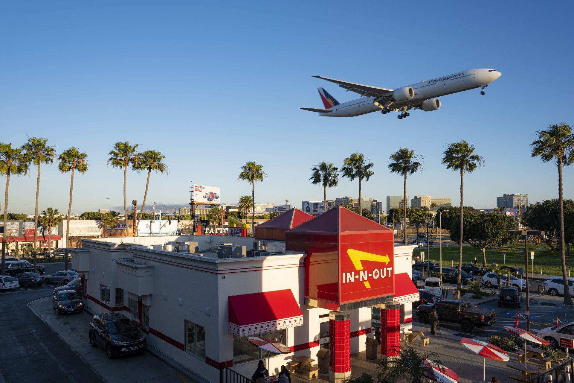An airplane is flying over an in-n-out restaurant