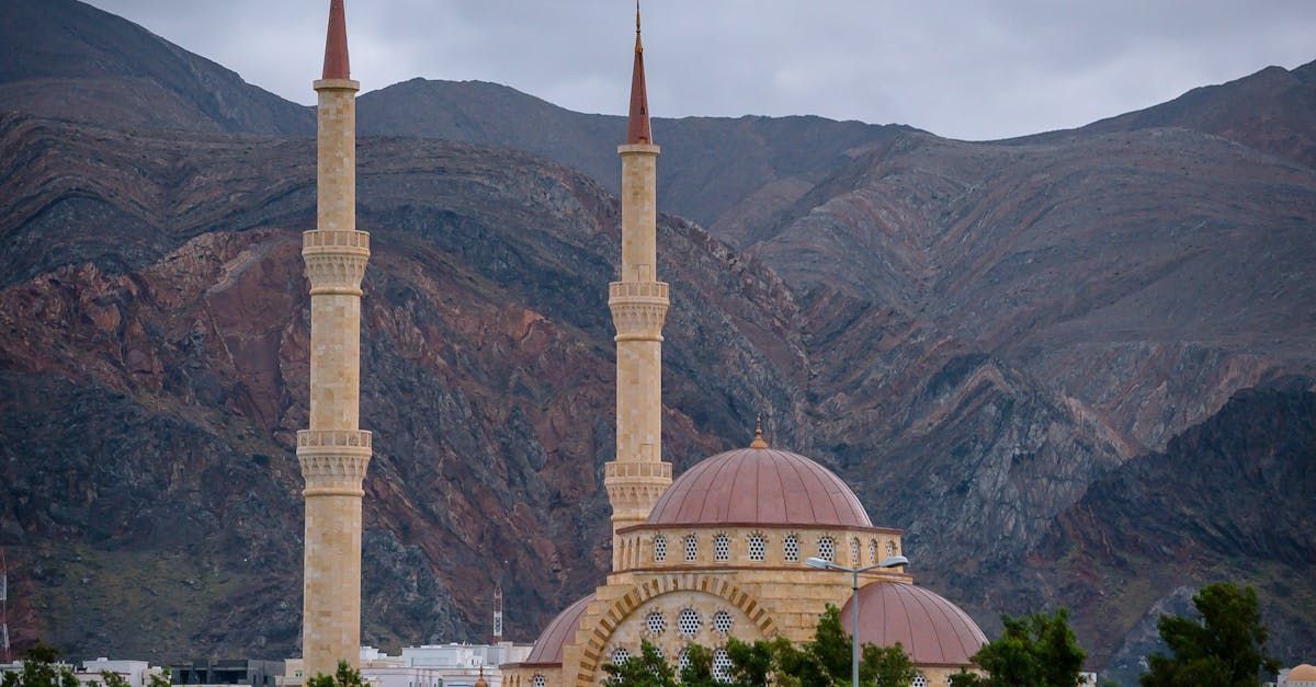 A mosque with two minaret tower in front of mountains.