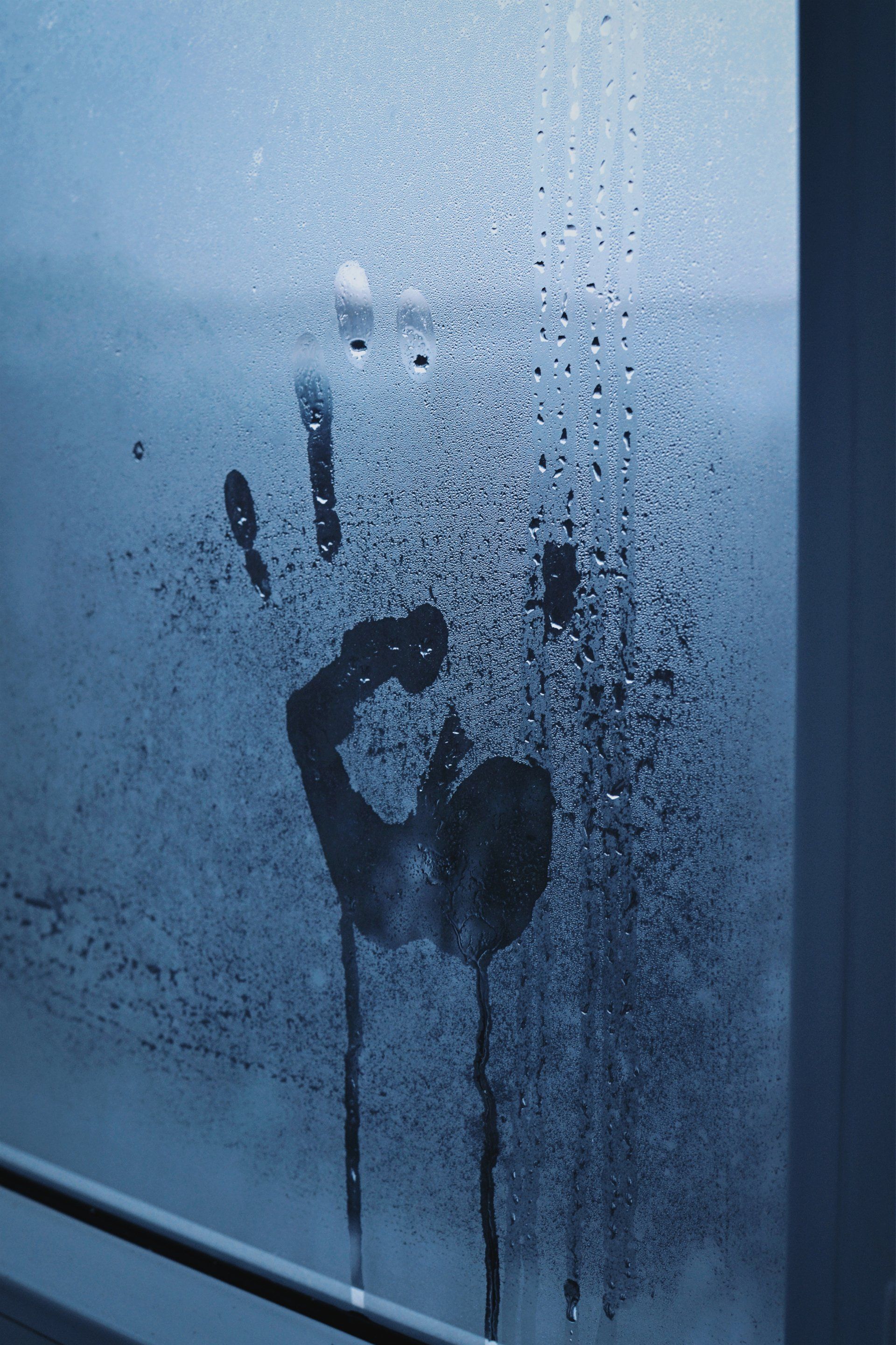 A picture of a hand print on a condensation on a window
