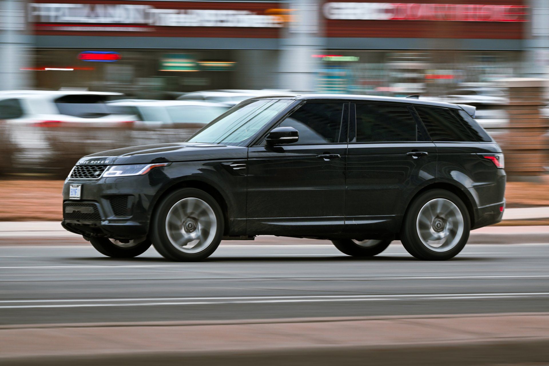 a black range rover sport is driving down a city street .