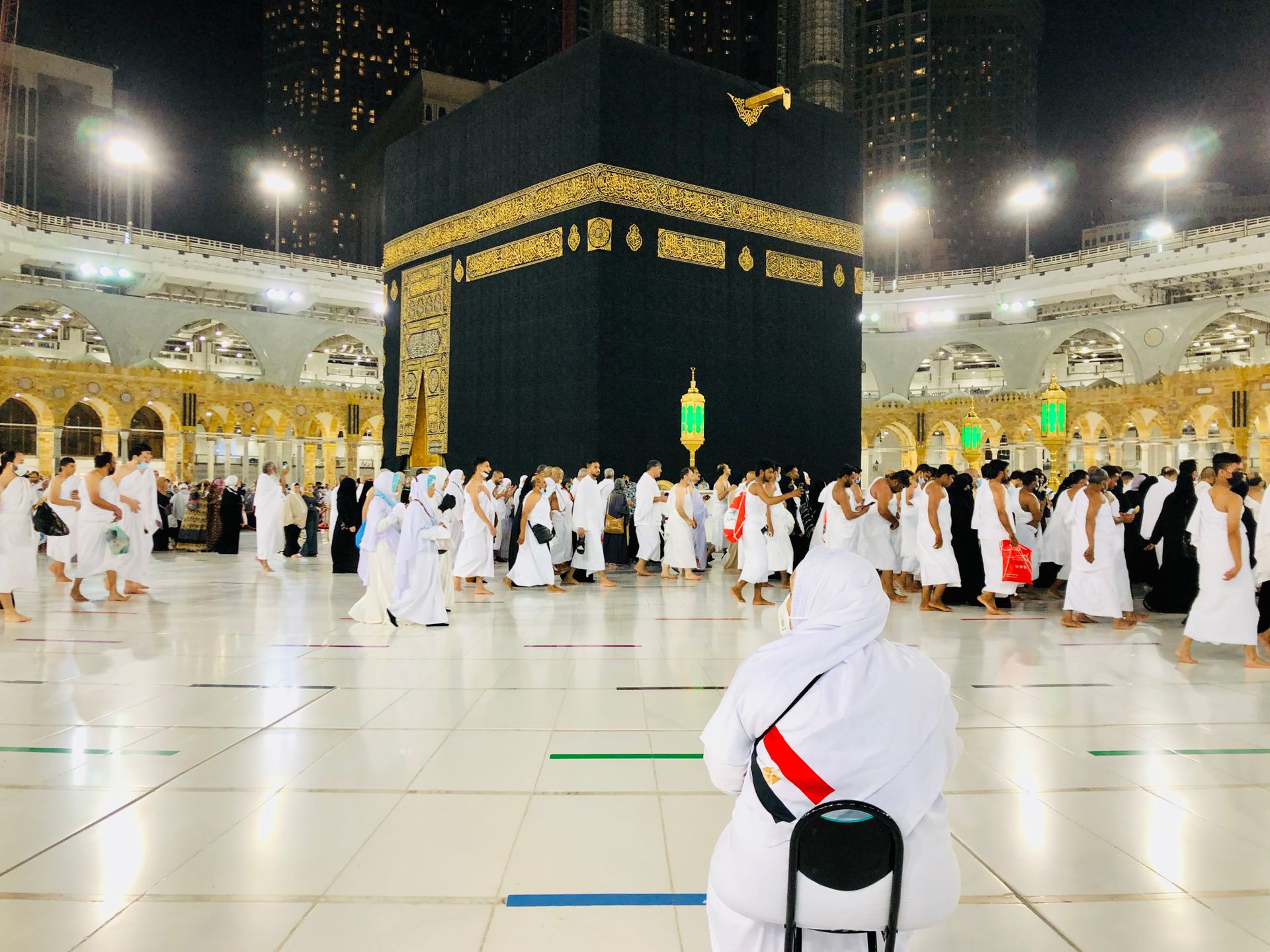 A group of people are standing in front of the kaaba in a mosque.