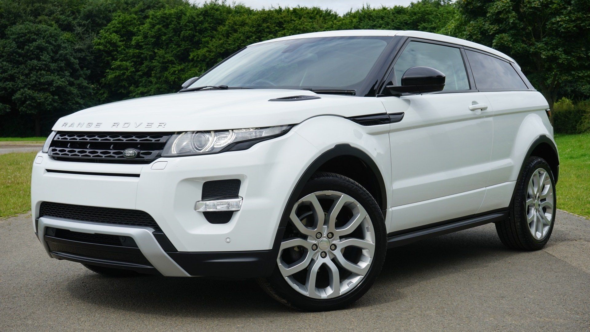 A white range rover evoque is parked on the side of the road.