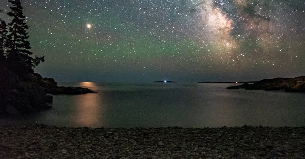 A night sky filled with lots of stars over a body of water.