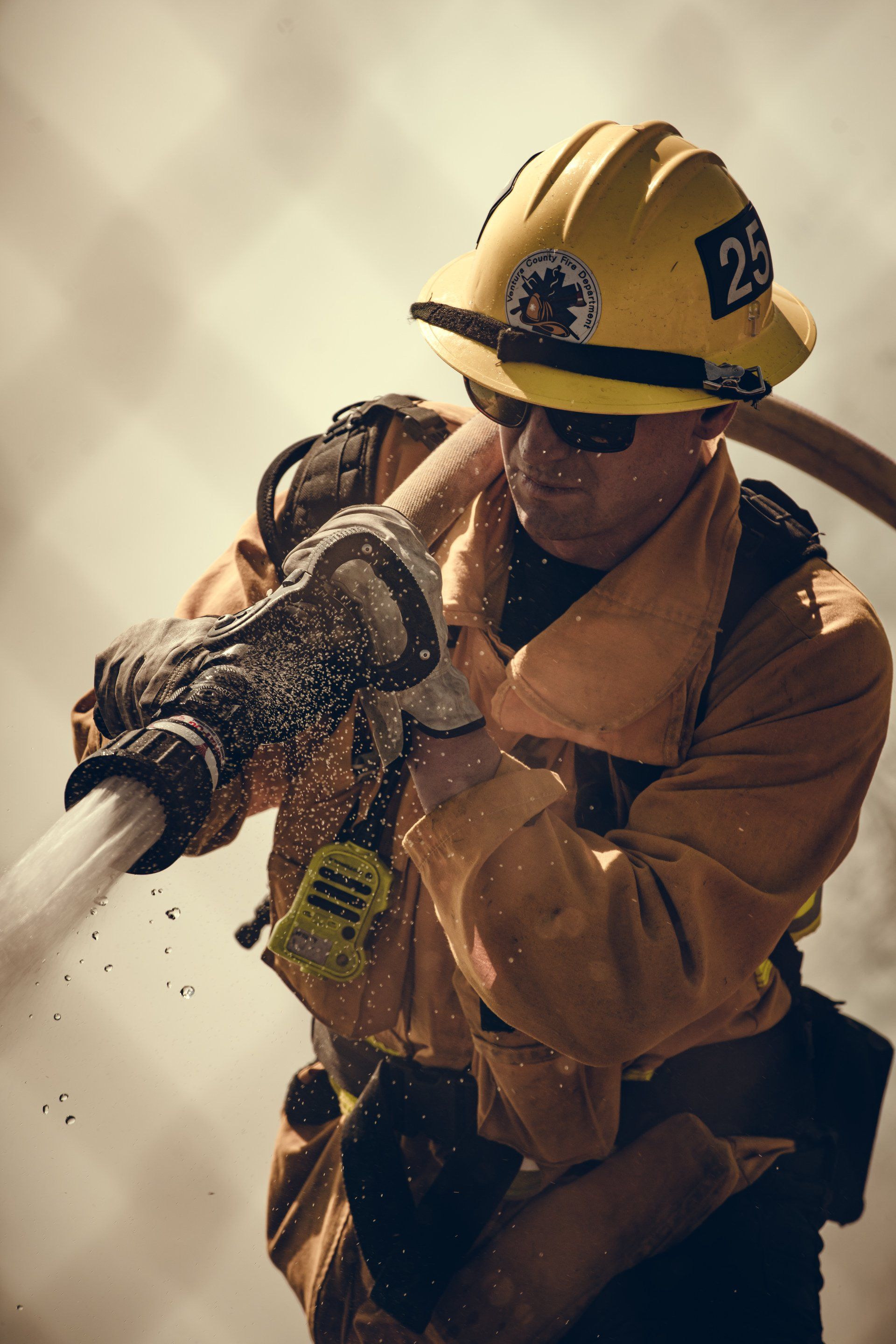 A fireman is spraying water from a fire hose.