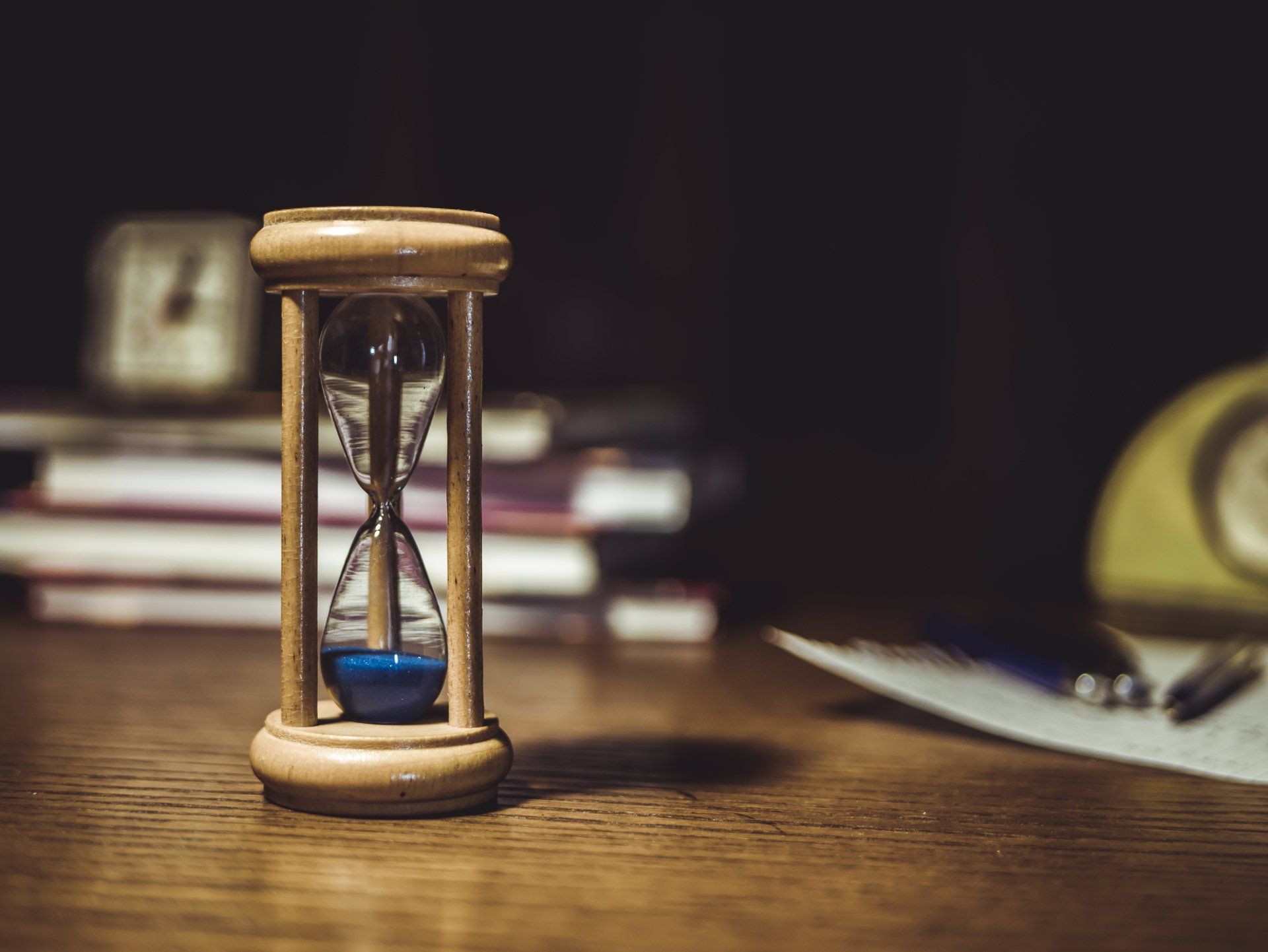 hour glass on an office desk with books in the background