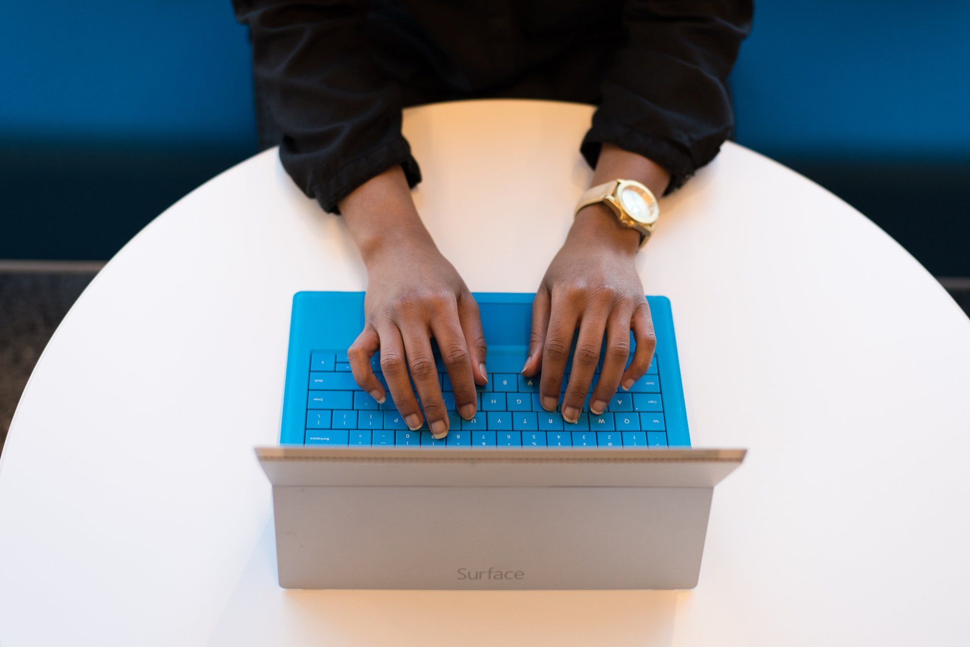 A person is sitting at a table typing on a laptop computer.