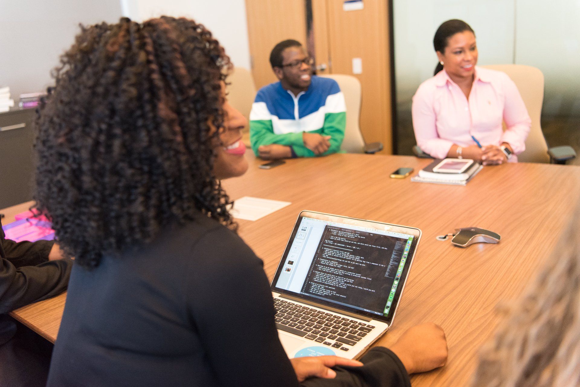 A group of people are sitting around a table with a laptop on it.