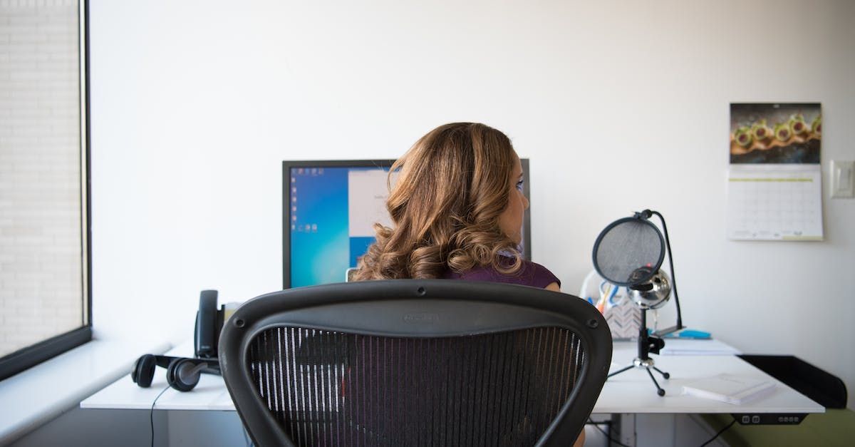 behind view of a woman sitting in an office chair at her office worstation