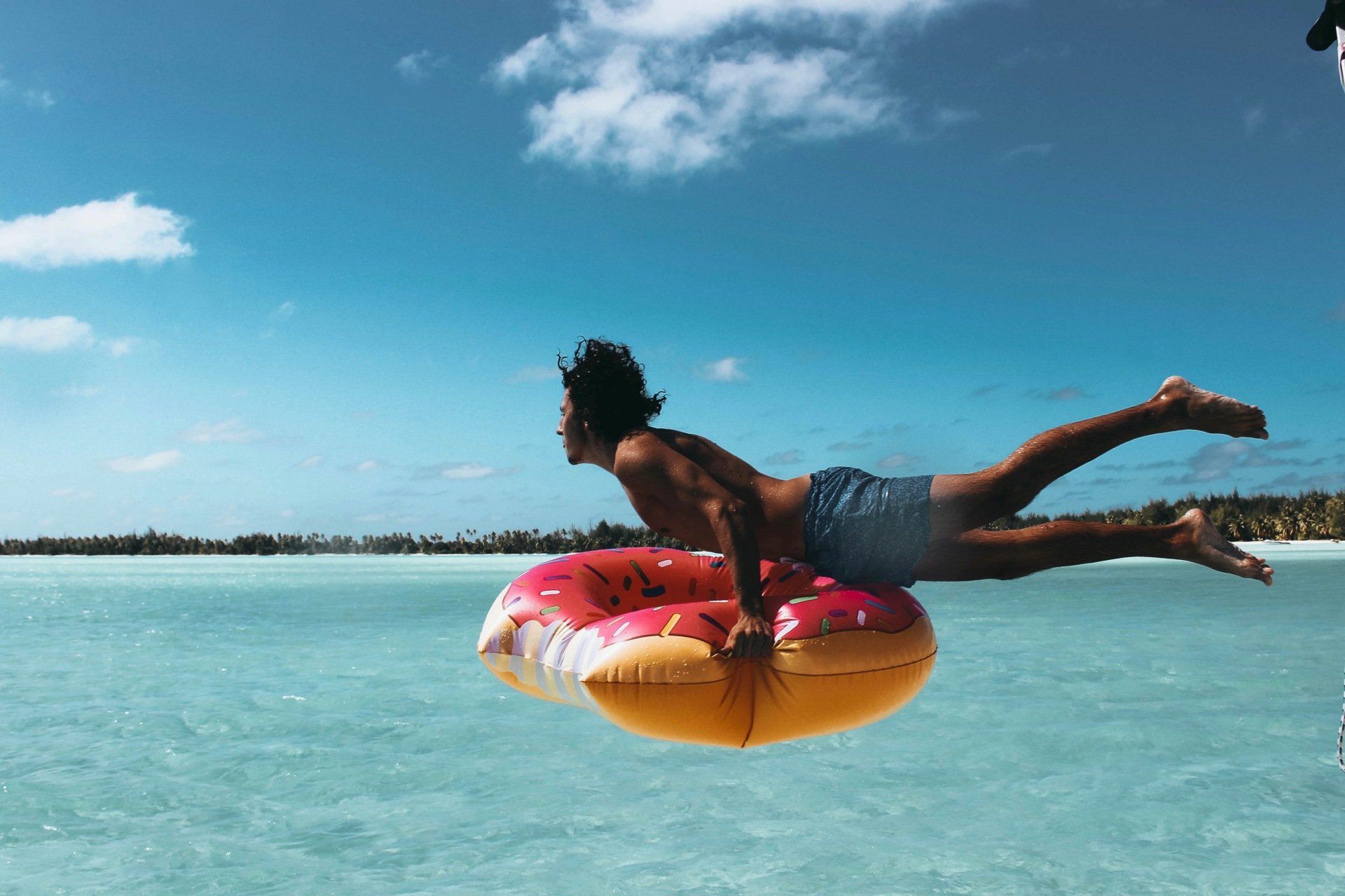 A man is floating on an inflatable donut in the ocean.