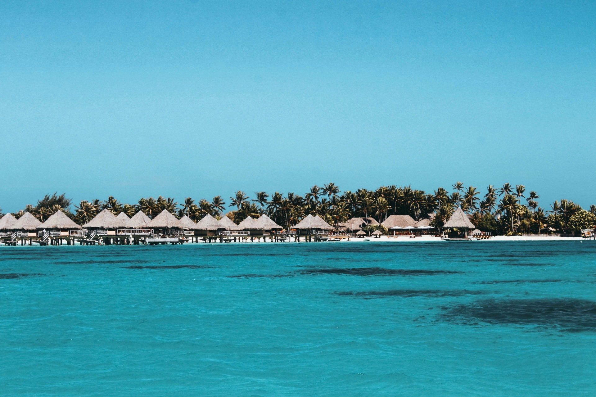 A row of bungalows in the middle of the ocean.