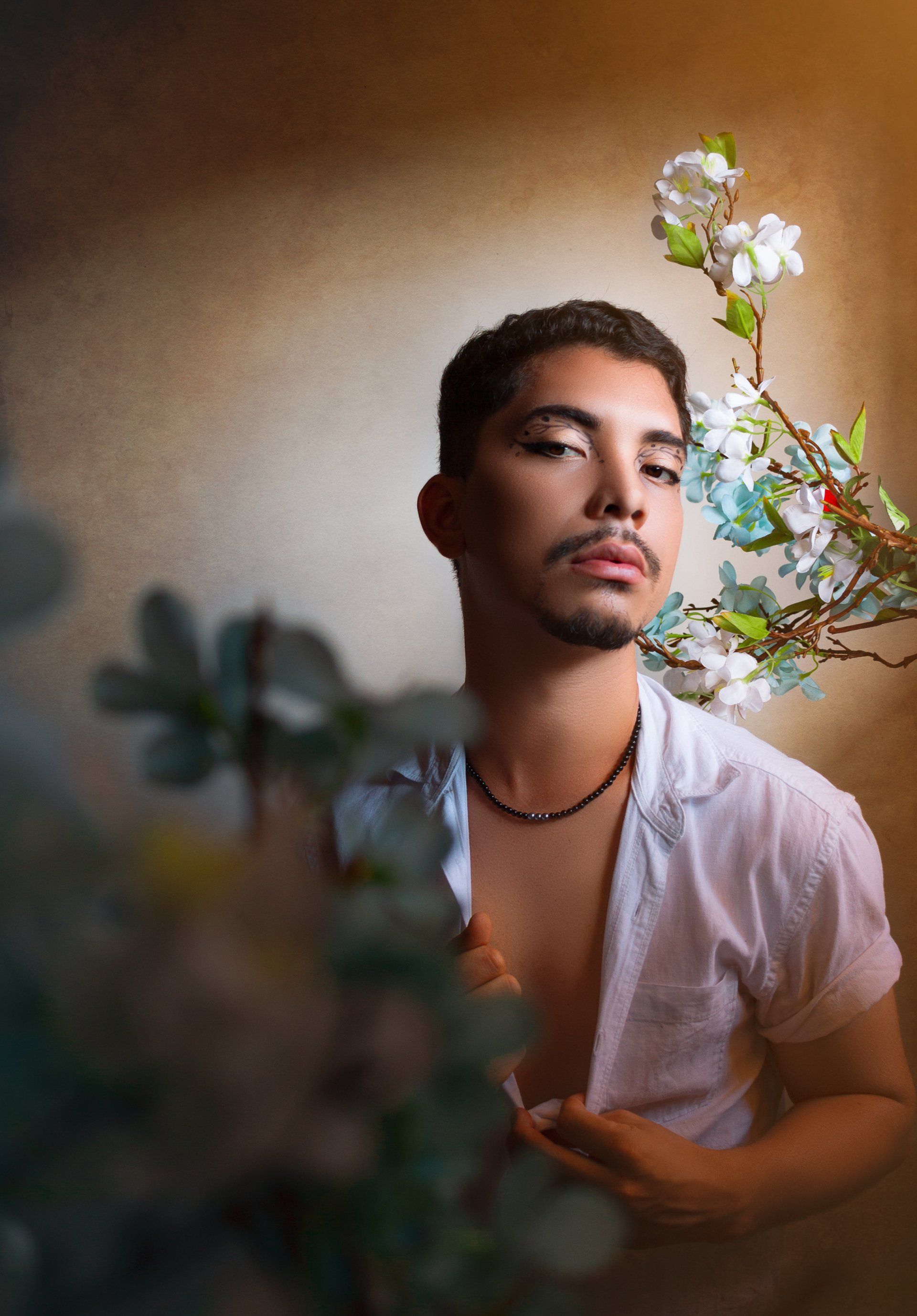 A man in a white shirt is standing next to a flower.