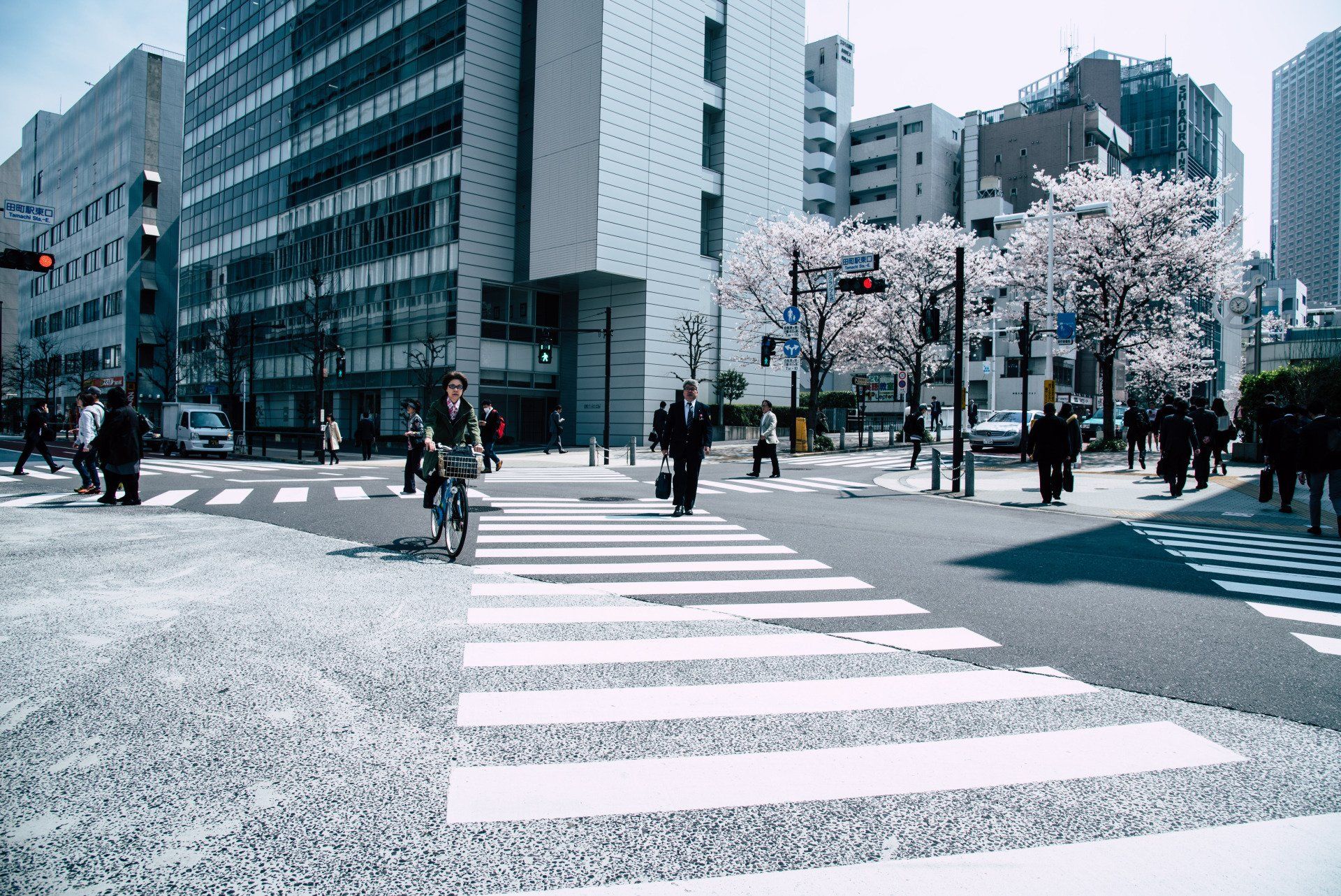 people crossing a street with a sign that says ' tokyo ' on it