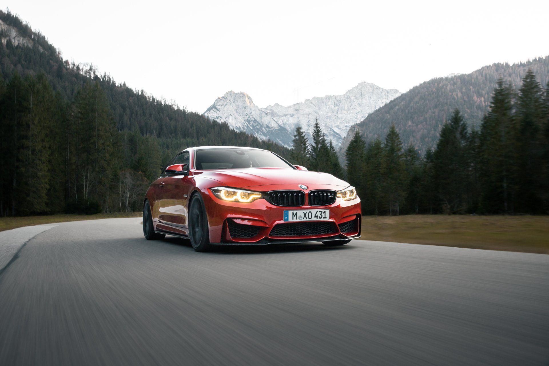 a red bmw m4 is driving down a mountain road .