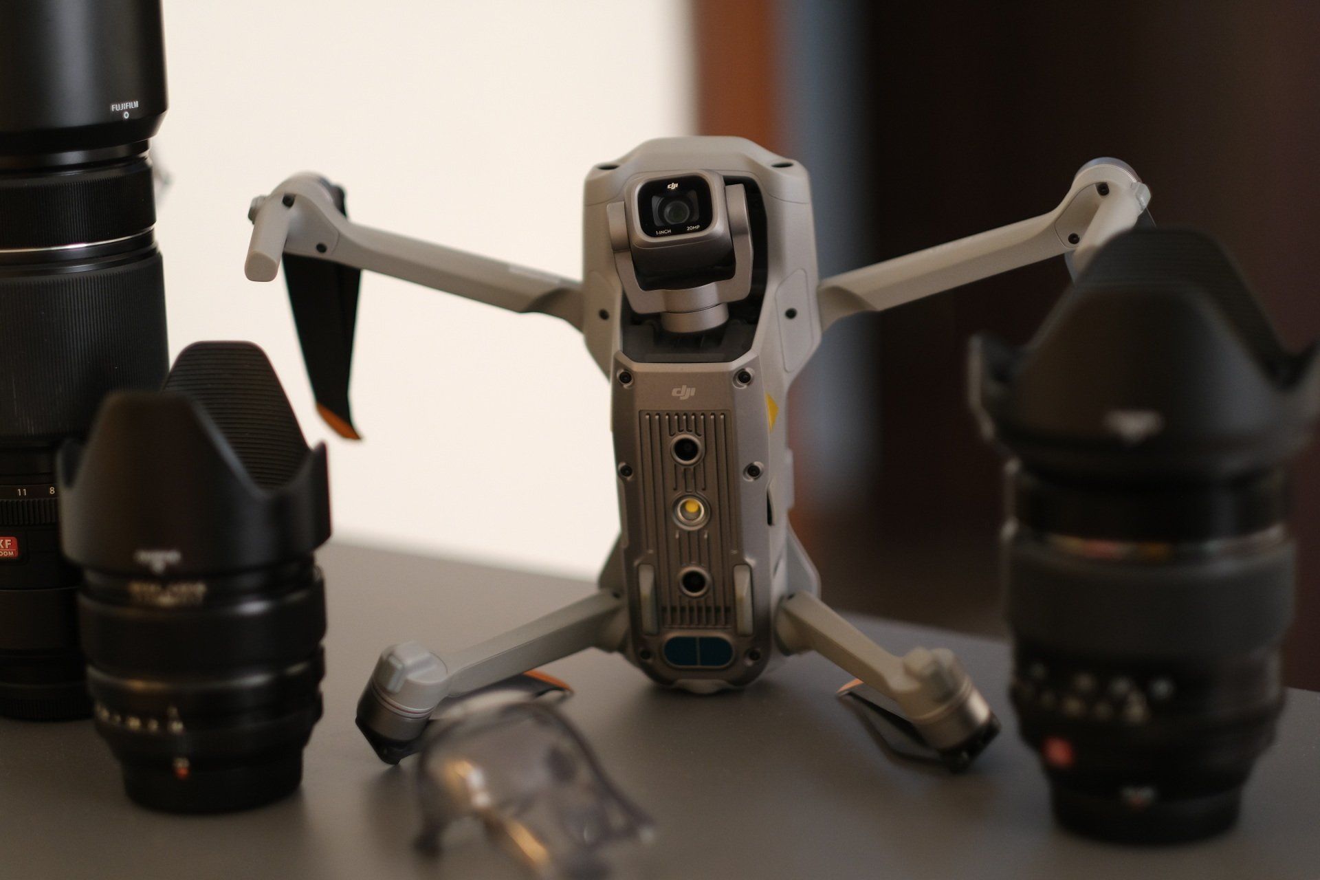 a drone is sitting on a table next to camera lenses .